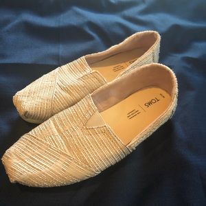 Cream colored, patterned, slip on Toms shoes